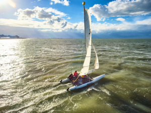 deelnemer die met een catamaran zeilt tijdens de Olympische Spelen op het strand en het water