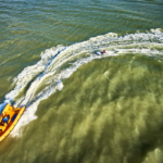 luchtfoto van de zee waar een boot een plank trekt tijdens de Olympische Spelen van Strand en Water
