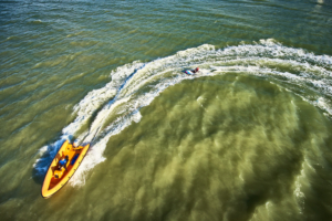 aerial view of the sea where a boat is pulling a board during the Beach & Water Olympics